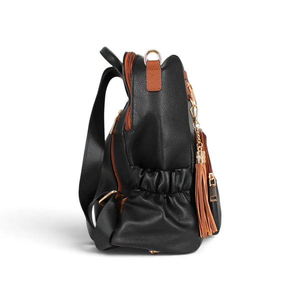 Sac à dos Maison Taïga noir et cognac avec pompon décoratif, vue de profil montrant les poches latérales et sangles