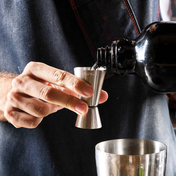 Versement d’un spiritueux dans le doseur double Final Touch au-dessus d’un shaker.