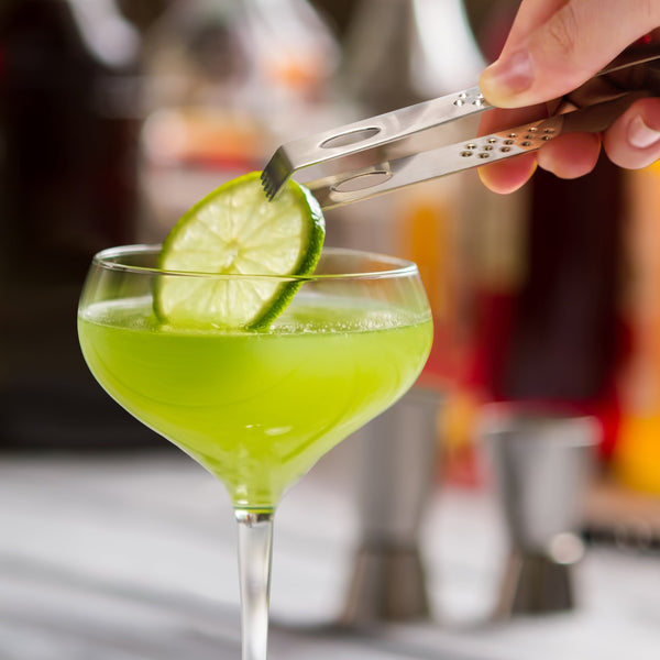 Pince de bar Final Touch déposant une tranche de lime sur un cocktail.