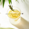 Pique à cocktail Final Touch posée sur un verre garni de citron et de romarin.